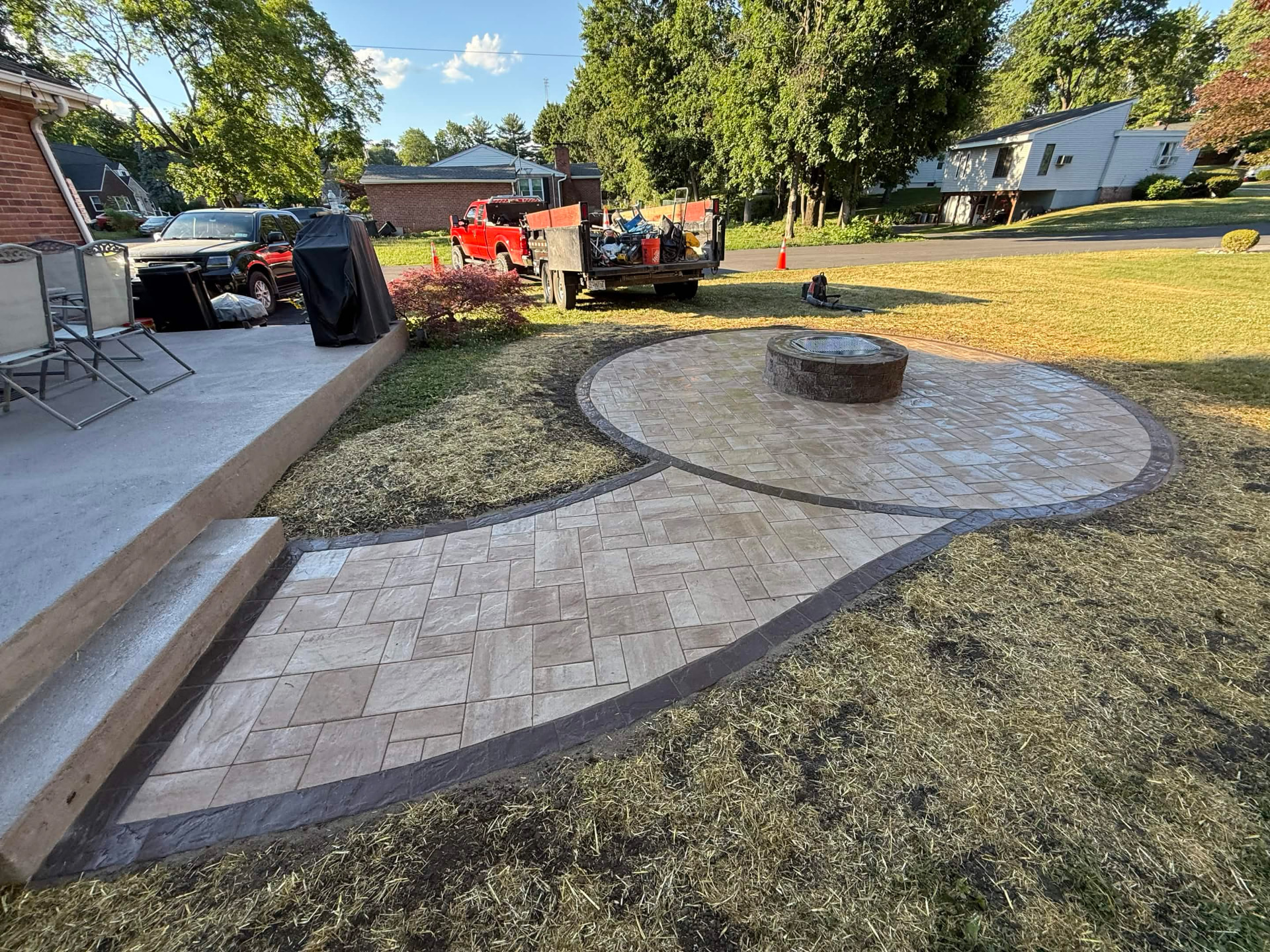 Paver patio with stone fire pit built by DL Full Renovation & Masonry